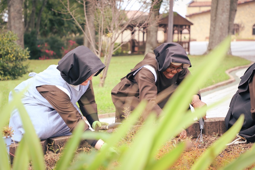 Smiling nuns working in their garden.