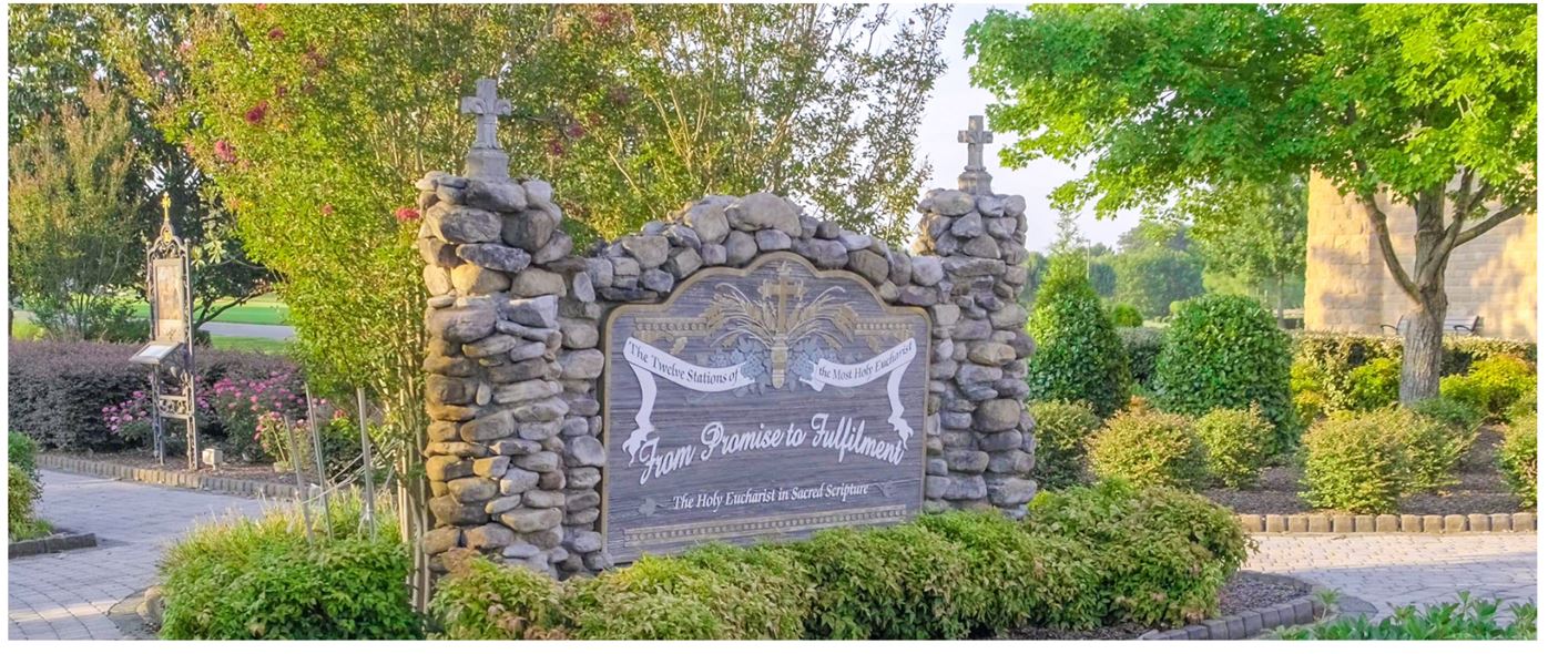 The ornate sign at the entrance to the Eucharistic Stations of the Cross Garden which reads: From Promise to Fulfillment.